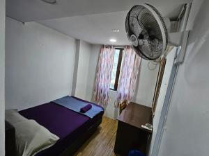 Habitación pequeña con cama y ventilador. en HOTEL Rampai Rooms, en Kuala Lumpur