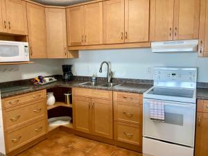 a kitchen with wooden cabinets and a sink and a microwave at Beachfront Walkout Condo in Qualicum Beach