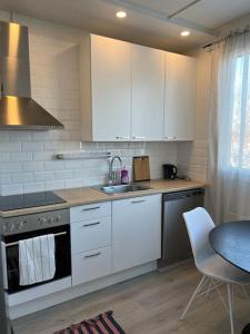 a kitchen with white cabinets and a sink and a table at Kustaan neliö in Kokkola