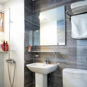 ein Badezimmer mit Waschbecken, Toilette und Spiegel in der Unterkunft The Naeun Stay in Seogwipo