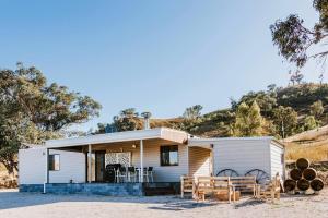 a small white house with chairs and tables at Canguri Boutique - A Memorable Farmstay near Mudgee in Mudgee