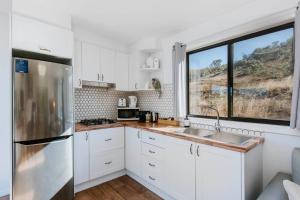 a kitchen with white cabinets and a sink and a window at Canguri Boutique - A Memorable Farmstay near Mudgee in Mudgee +33 photos