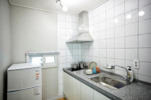 eine kleine Küche mit Spüle und Kühlschrank in der Unterkunft The Naeun Stay in Seogwipo + 5 Fotos