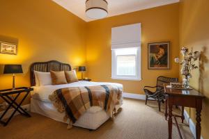 a bedroom with a bed with yellow walls and a window at Luxury at Lauralla - An Elegant Victorian Escape in Mudgee