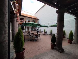 een patio met tafels en stoelen en groene parasols bij Casona Tobar Hotel in Rocafuerte