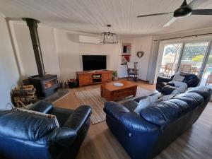 sala de estar con sofás de cuero y chimenea en Pipeclay Cottage - Farmstay Vibes and Chic Design, en Eurunderee