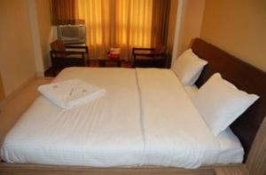 a bedroom with a large bed with white sheets and pillows at Hotel Bhagyalaxmi , Shirdi in Shirdi