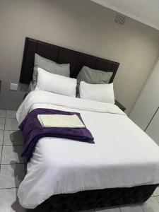 a large bed with white sheets and pillows at Moon Memories Guesthouse in Welkom