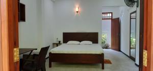 a bedroom with a bed and a table and a desk at Sunil's Villa in Hikkaduwa