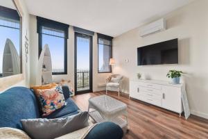 a living room with a blue couch and a tv at Sails by the Bay - Ocean Views - Wi-Fi - Netflix in Frankston