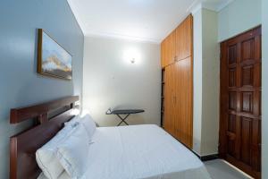 1 dormitorio con 1 cama y puerta de madera en THEATRE OF DREAMS HOMES en Kampala