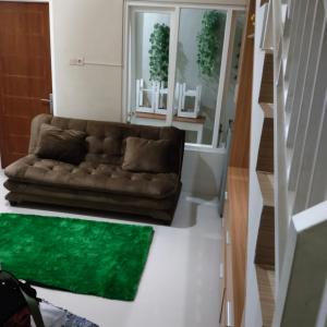 uma sala de estar com um sofá castanho e um tapete verde em Villa keluarga sejahtera em Batu