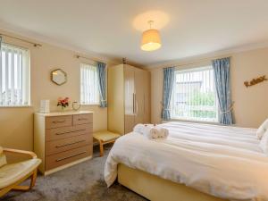 a bedroom with a white bed and a dresser and windows at 3 Bed in Harlech 42153 in Harlech
