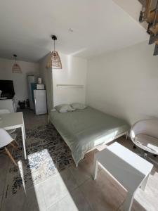 a bedroom with a bed and a table and a refrigerator at Studio cosy et climatisé - Tout équipé - Parking privé in Roaix