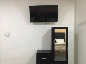 TV de pantalla plana en una pared sobre un espejo en Chuburná suites Depa Jr, en Chuburná