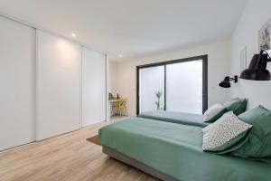 1 dormitorio con cama verde y ventana grande en Magnifique Appartement Plage Cavalière Terrasse 3 Chambres Garage, en Le Lavandou