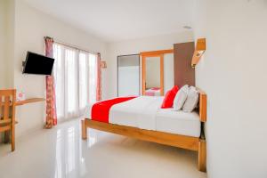 1 dormitorio con 1 cama grande con almohadas rojas y blancas en OYO 90319 Angler Guest House Malang, en Malang
