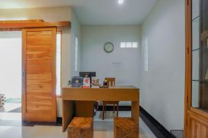 una habitación con una mesa y un reloj en la pared en OYO 90319 Angler Guest House Malang, en Malang
