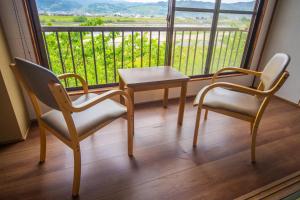 duas cadeiras e uma mesa em frente a uma janela em Ryokan Toyotomi em Asakura
