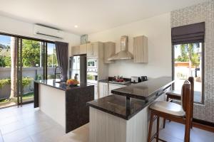 a kitchen with white cabinets and black counter tops at 3BR Villa next MissionHills Golf Villa Argent 7 in Ban Muang Mai