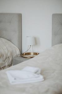 a white bed with a lamp on a side table at Verslo Klasė-easy to stay in Panevėžys