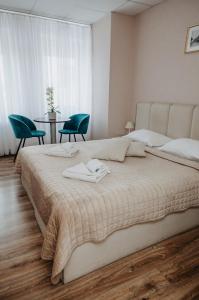 a bedroom with a large bed with two chairs and a table at Verslo Klasė-easy to stay in Panevėžys