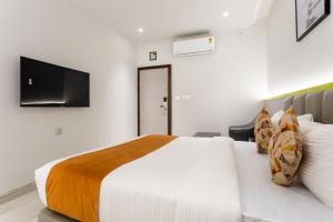 a bedroom with a large white bed and a flat screen tv at FabHotel Prime Oasis Orange in Bhopal
