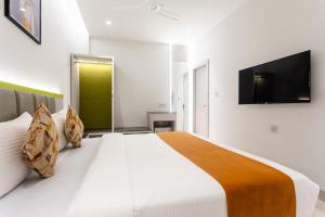 um quarto com uma grande cama branca e uma televisão de ecrã plano em FabHotel Prime Oasis Orange em Bhopal