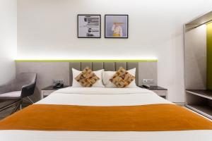 a bedroom with a large bed and a chair at FabHotel Prime Oasis Orange in Bhopal