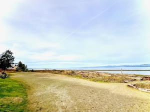 a dirt road next to a body of water at Beachfront Walkout Condo in Qualicum Beach