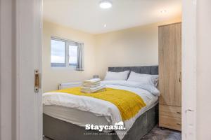 ein Schlafzimmer mit einem großen Bett und einer gelben Decke in der Unterkunft Urban Comfort 4-bed House - Free Wi-fi & Parking in Manchester