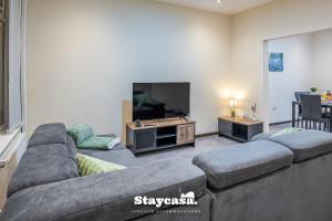 ein Wohnzimmer mit einem großen Sofa und einem Flachbild-TV in der Unterkunft Urban Comfort 4-bed House - Free Wi-fi & Parking in Manchester