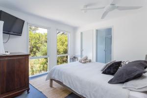a bedroom with a bed and a tv and windows at Stroll to the Sea - Sun-drenched Seaside Lifestyle in Rye