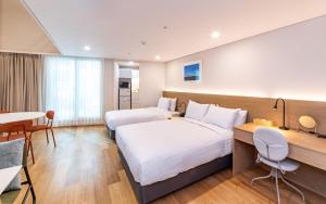 Habitación de hotel con 2 camas y mesa en New Seoul Hotel Myeongdong, en Seúl