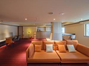 an orange couch in a living room with a table at Rich & Free Hotel - Fuzhong 富逸旅趣-板橋府中館 in Taipei