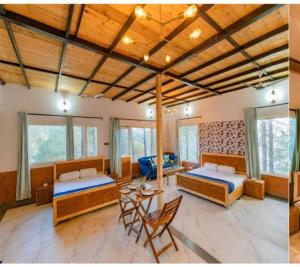 a bedroom with two beds and a table and chairs at Pinewood Nirvana Jungle Resort Shoghi in Shimla