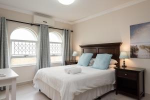 a bedroom with a bed with blue pillows and two windows at La Mustique 4 in Ballito