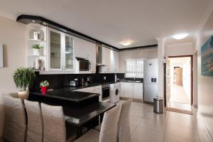 a kitchen with white cabinets and a black counter top at La Mustique 4 in Ballito