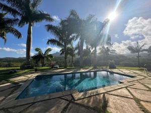 a swimming pool with palm trees in the background at Villa Kamaya, Chamarel in Chamarel +49 photos