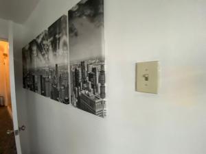 a wall with two pictures of a city on it at Cozy apartment with city skyline. Easy commute midtown Manhattan. in Jersey City