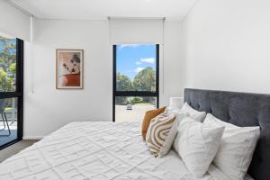 een slaapkamer met een groot bed met witte lakens en kussens bij Addison's Escape - A Breezy Beachfront Beauty in Shellharbour
