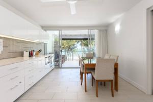 a kitchen with white cabinets and a table with chairs at Aspen - Beachfront Bliss at The Drift in Palm Cove
