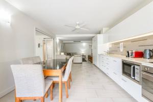 a kitchen with white cabinets and a table and chairs at Aspen - Beachfront Bliss at The Drift in Palm Cove