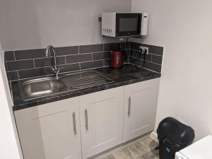 a kitchen counter with a sink and a microwave at Private garden annexe with kitchenette in Gedney