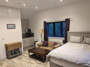a bedroom with a bed and a couch and a table at Private garden annexe with kitchenette in Gedney