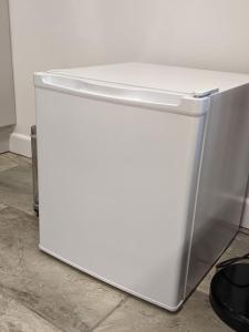a white refrigerator sitting on top of a floor at Private garden annexe with kitchenette in Gedney