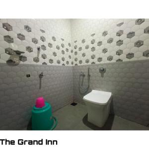 a bathroom with a white toilet and a shower at The Grand Inn in Nirmal