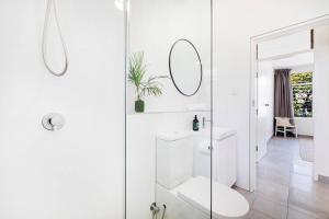 a white bathroom with a toilet and a mirror at 'The Botanica' A Triple-apartment Residence in Nightcliff in Darwin +34 photos