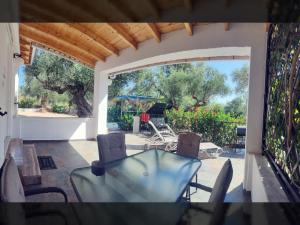 a patio with a glass table and chairs on a patio at ArokariApartments in Koroni
