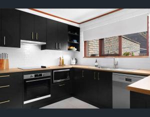 a kitchen with black cabinets and a window at Beachfront beauty in Broulee